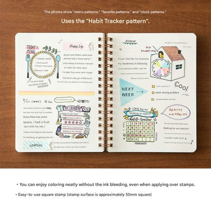 Open spiral-bound notebook displaying habit tracker patterns on a wooden surface.