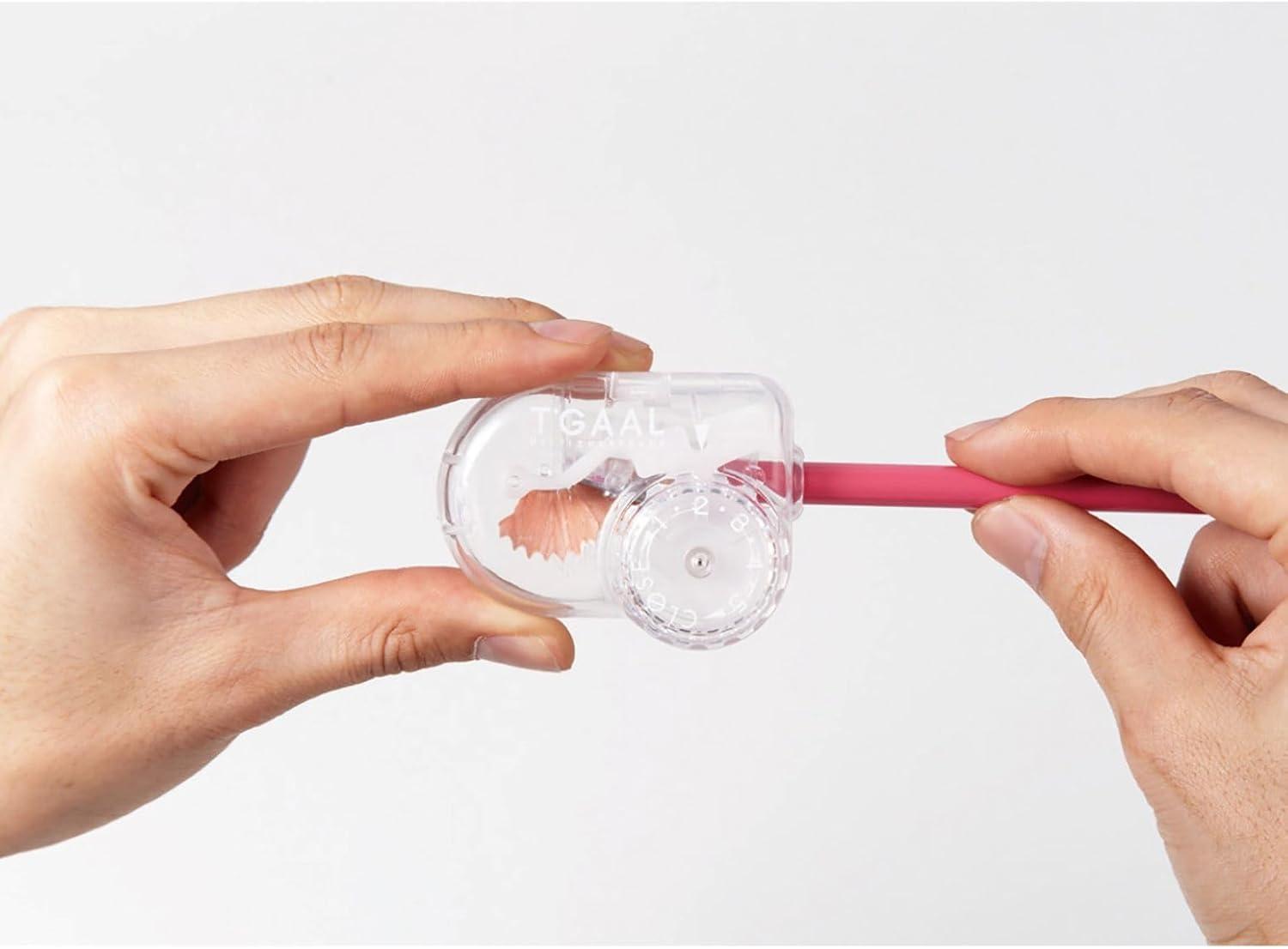 Person using a clear plastic tool to apply pink lip balm on a white background
